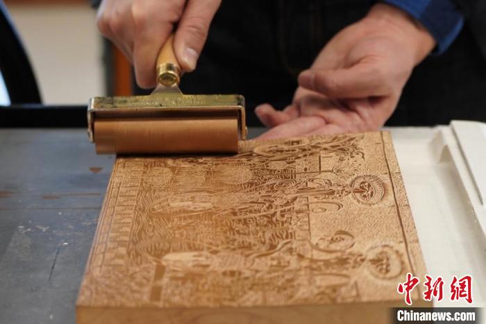 圖為徐晉林工作室工作人員正在給雕好壁畫的版面滾油墨?！【琶赖┰?　攝