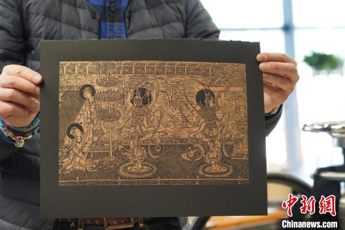 圖為手工書藝人展示敦煌雕版壁畫印刷品。　九美旦增 　攝