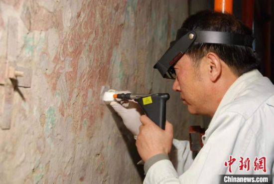 敦煌研究院研究員樊再軒進(jìn)行壁畫修復(fù)。(資料圖)張?jiān)莆?攝